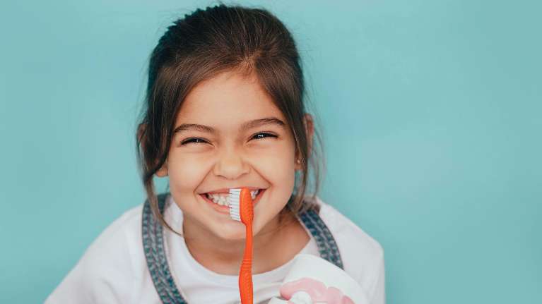 Young girl smiling with toothbrush in front of face, los gatos ca
