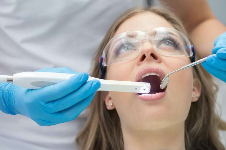 A woman receiving a dental cleaning, showcasing oral health benefits and dental implants.