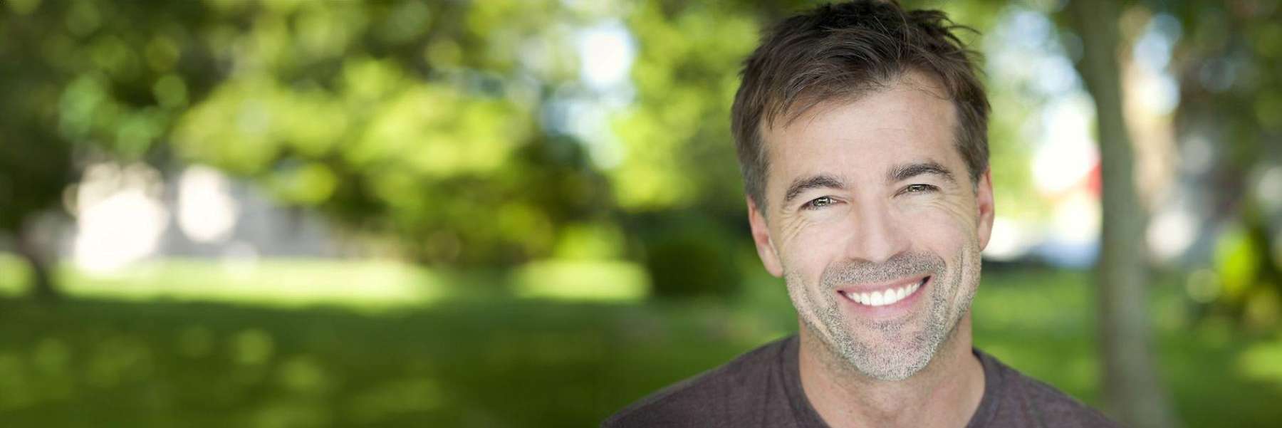 A man smiles against a green background, reflecting hope for TMJ treatment in Los Gatos, CA.