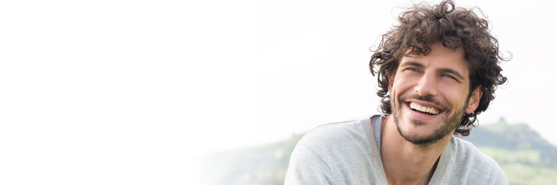 man with curly hair smiling | dental implants los gatos ca